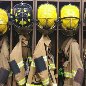 A,lineup,of,firemens,helmets,and,turnout,gear,in,a